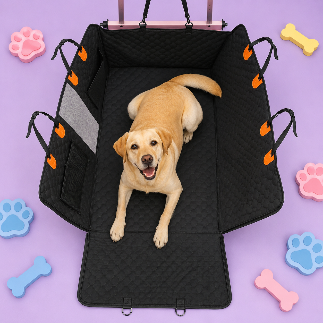 A yellow Labrador retriever lies inside a black padded dog crate with orange accents, set against a lavender background decorated with colorful bone and paw print shapes.
