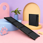 A black metal pet ramp with a textured non-slip surface, shown both folded and unfolded in a stylized studio setup with pastel props including a plant, paw print, and arch shapes.